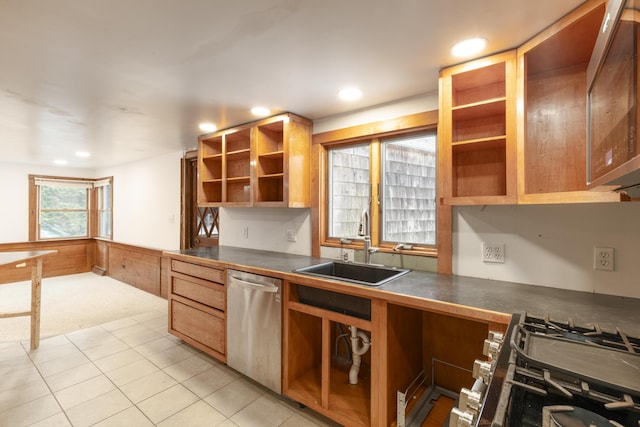 kitchen with a sink, light colored carpet, open shelves, stainless steel dishwasher, and dark countertops