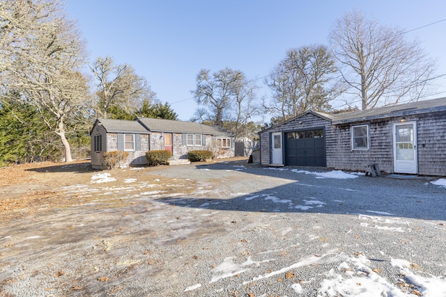 single story home featuring driveway, an outdoor structure, and an attached garage