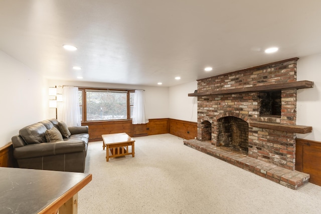 carpeted living room with a brick fireplace, wooden walls, wainscoting, and recessed lighting
