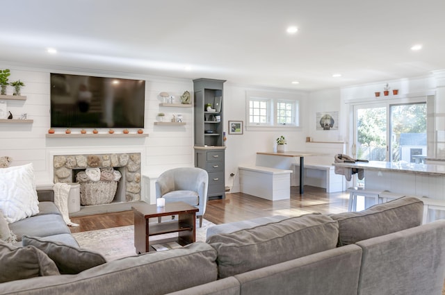 living room featuring light hardwood / wood-style floors, ornamental molding, and a fireplace