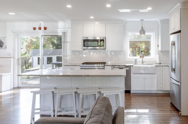 kitchen with decorative backsplash, sink, white cabinets, pendant lighting, and stainless steel appliances