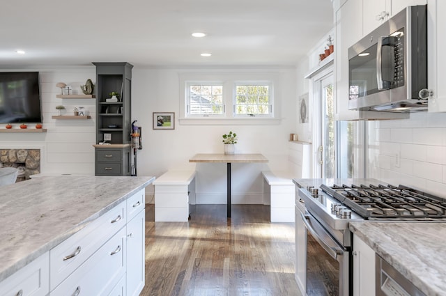 kitchen with white cabinetry, light stone countertops, dark hardwood / wood-style floors, decorative backsplash, and stainless steel appliances