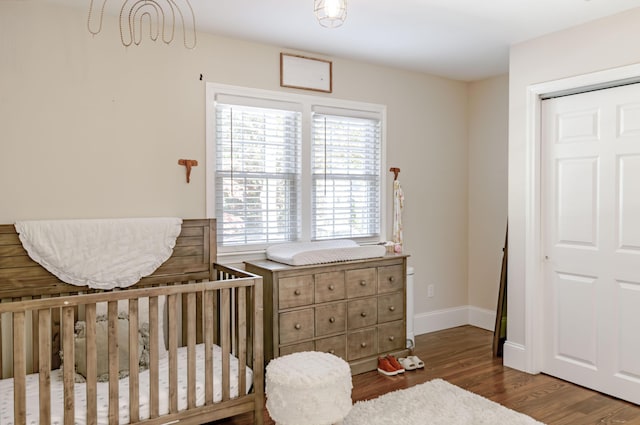 bedroom with wood-type flooring, a closet, and a nursery area