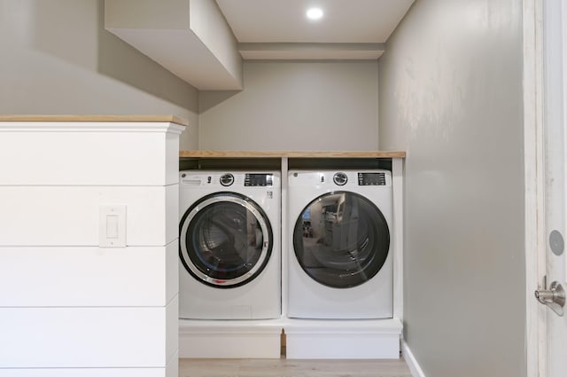 clothes washing area featuring light hardwood / wood-style floors and washing machine and dryer