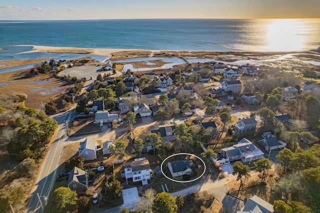 aerial view at dusk featuring a water view and a beach view