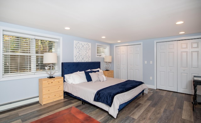 bedroom with multiple closets, a baseboard heating unit, and dark wood-type flooring