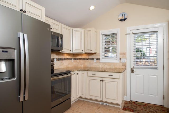 kitchen with light stone countertops, stainless steel appliances, tasteful backsplash, vaulted ceiling, and light tile patterned floors