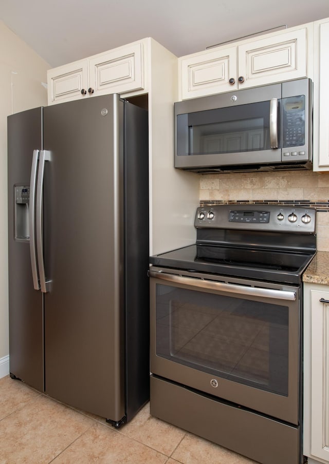 kitchen with light stone countertops, appliances with stainless steel finishes, white cabinetry, tasteful backsplash, and light tile patterned flooring