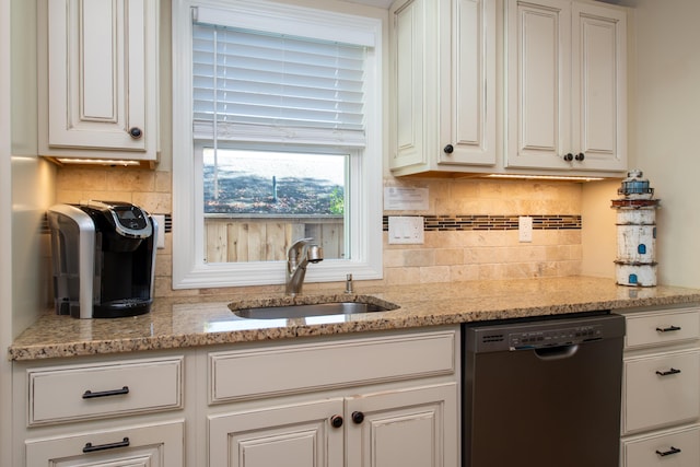 kitchen featuring light stone counters, sink, white cabinetry, and black dishwasher