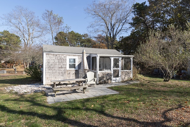 rear view of property featuring a sunroom, a patio area, and a yard