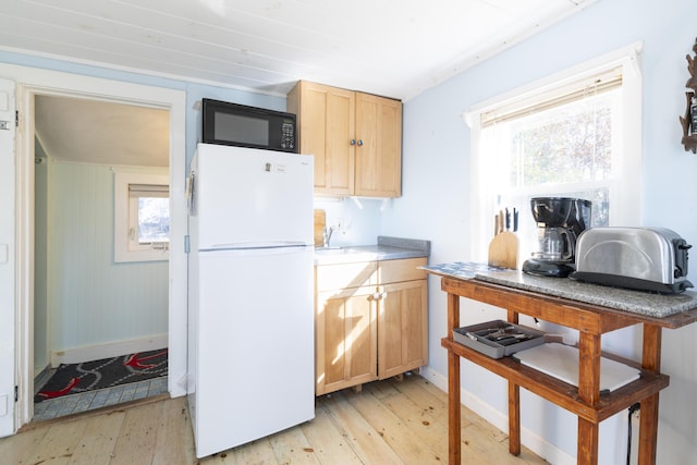 kitchen featuring light brown cabinets, light hardwood / wood-style floors, and white fridge