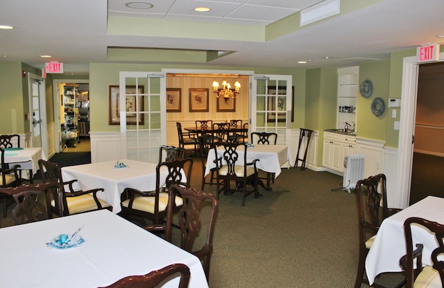110 Dillingham Ave Unit 215U, Falmouth, MA 02540 - dining area featuring radiator, a wainscoted wall, a chandelier, dark colored carpet, and a tray ceiling