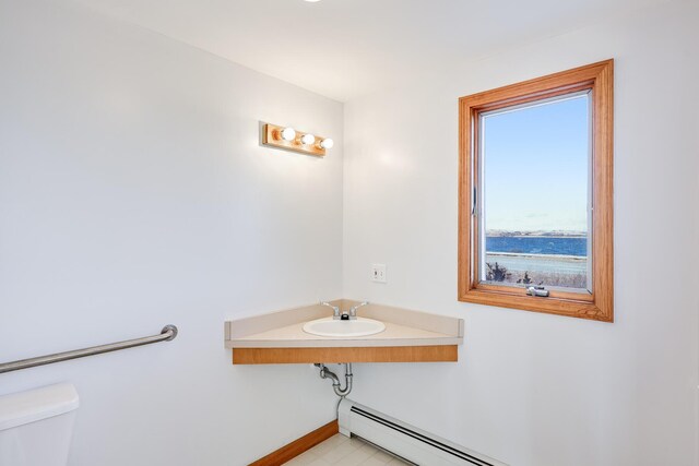 bathroom featuring sink, toilet, and a baseboard heating unit