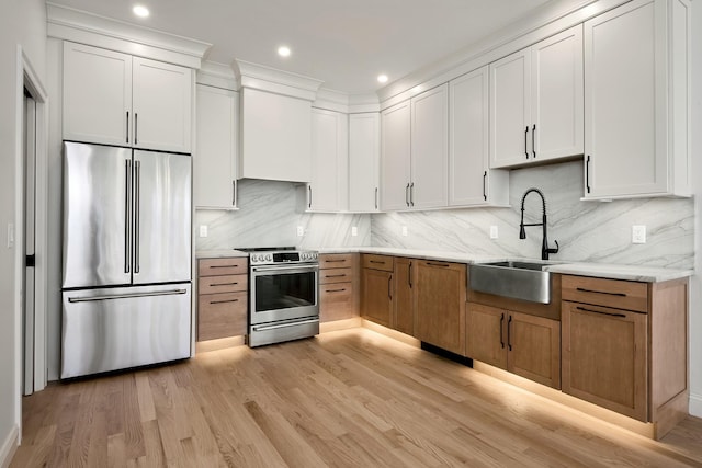 kitchen with stainless steel appliances, decorative backsplash, light wood-style flooring, and a sink