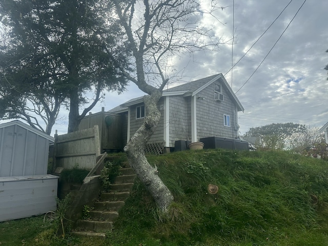 view of side of property with an outdoor structure, a shed, and fence