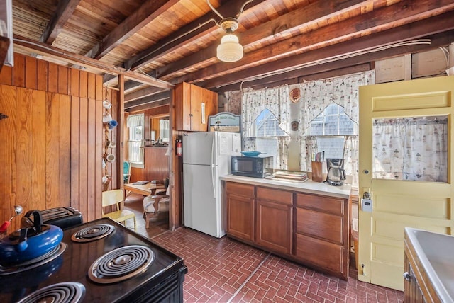 5 Spurr Rd, Pocasset, MA 02559 - kitchen featuring black appliances, wooden walls, brick patterned floors, brown cabinetry, and light countertops
