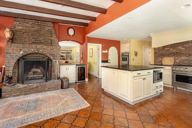 kitchen with beamed ceiling, a brick fireplace, wine cooler, and appliances with stainless steel finishes