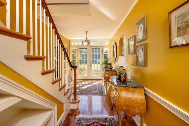 entrance foyer with wood-type flooring, ornamental molding, and french doors