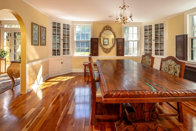 dining room featuring hardwood / wood-style flooring, ornamental molding, a healthy amount of sunlight, and an inviting chandelier