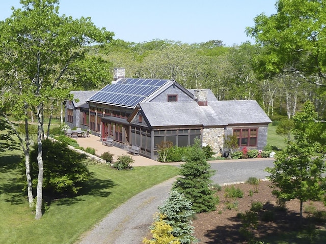 71 Stoney Hill Rd, Tisbury, MA 02568 - view of front of house with solar panels, a chimney, stone siding, and a patio area