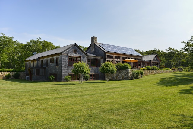 71 Stoney Hill Rd, Tisbury, MA 02568 - back of house featuring a yard, a chimney, roof mounted solar panels, and a sunroom