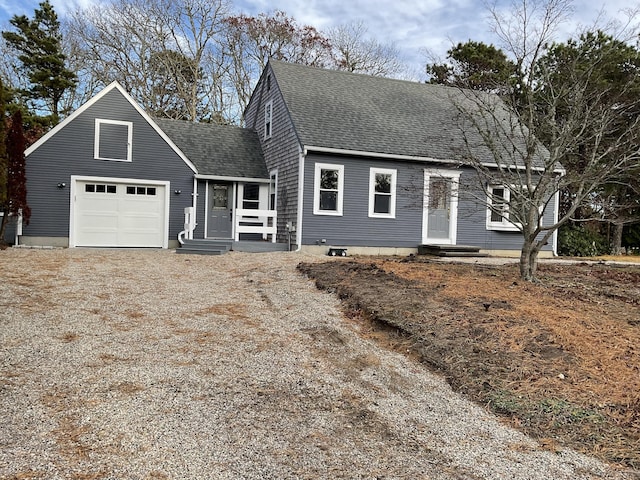 view of front of property featuring an attached garage, driveway, and a shingled roof