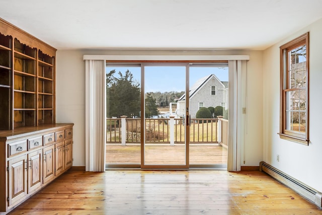 doorway with a baseboard radiator, a healthy amount of sunlight, and light hardwood / wood-style floors