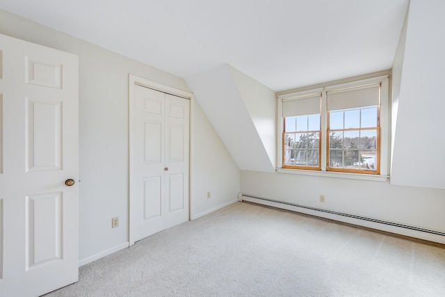 additional living space with vaulted ceiling, light carpet, and a baseboard heating unit