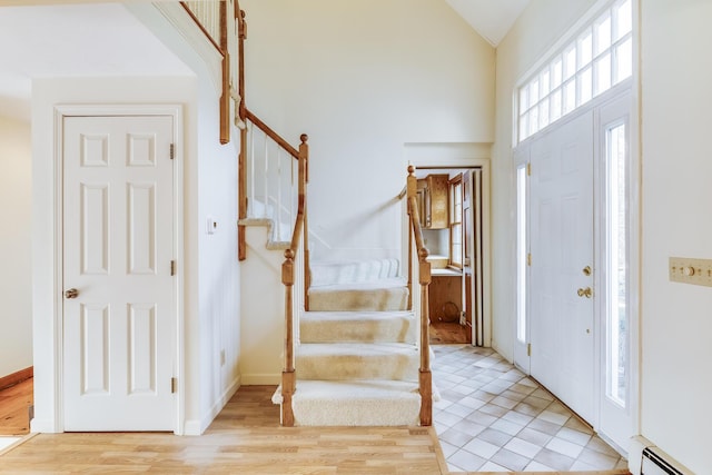 entrance foyer featuring light tile patterned flooring, vaulted ceiling, and a baseboard heating unit