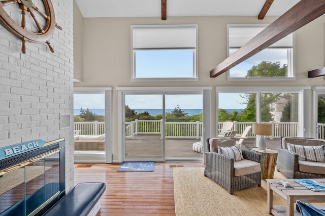 7 Dunes Rd, Harwich Port, MA 02646 - living area with beam ceiling, a high ceiling, wood finished floors, healthy amount of natural light, and a fireplace