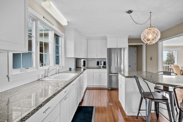 7 Dunes Rd, Harwich Port, MA 02646 - kitchen with freestanding refrigerator, a kitchen breakfast bar, white cabinetry, light wood-type flooring, and dark stone countertops