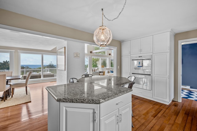 7 Dunes Rd, Harwich Port, MA 02646 - kitchen featuring double oven, hardwood / wood-style flooring, a kitchen island, white cabinets, and decorative light fixtures