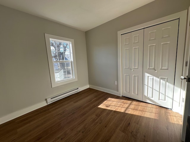 unfurnished bedroom with a baseboard radiator, a closet, and dark hardwood / wood-style flooring