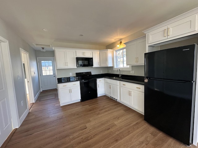 kitchen featuring black appliances, white cabinetry, dark wood-type flooring, and a healthy amount of sunlight