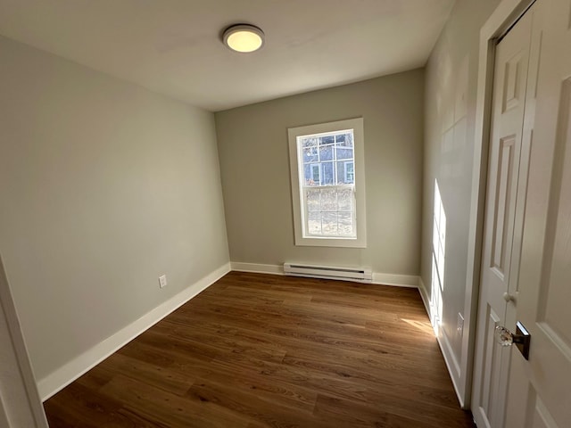 spare room with dark wood-type flooring and a baseboard heating unit