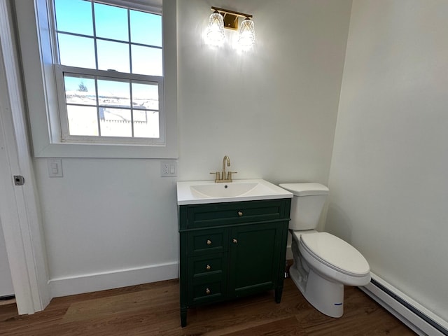 bathroom with vanity, toilet, a baseboard heating unit, and wood-type flooring