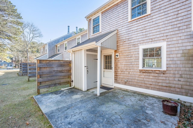 view of exterior entry featuring a patio area and fence