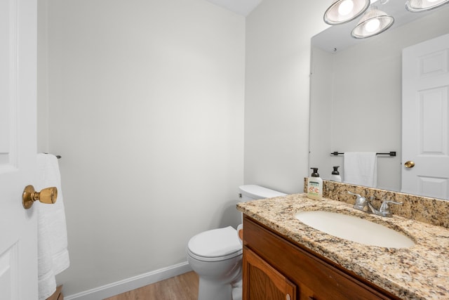 bathroom with baseboards, toilet, wood finished floors, and vanity