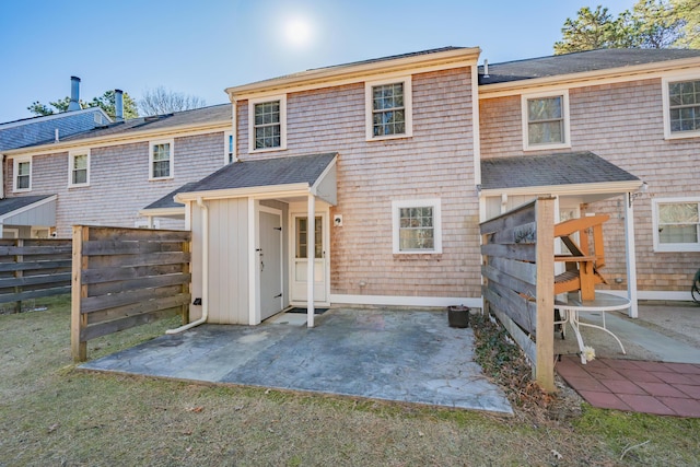 rear view of house with a patio, fence, and a shingled roof