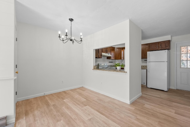 unfurnished dining area with baseboards, a chandelier, and light wood finished floors