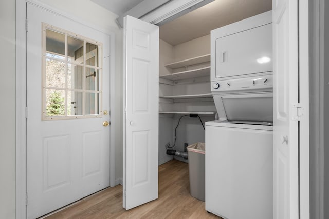 clothes washing area with laundry area, stacked washer / drying machine, and light wood-style floors