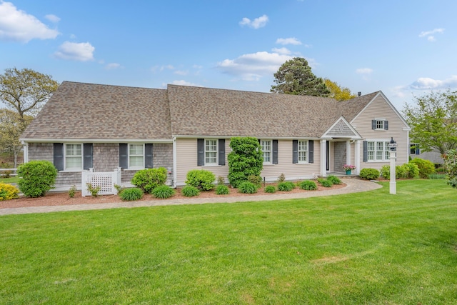 view of front facade with a front yard and a shingled roof