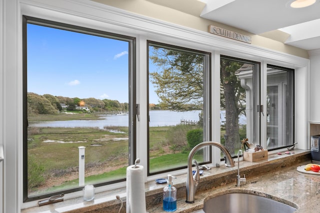 kitchen view of a water view, a sink, and stone counters