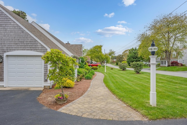 view of property exterior featuring a lawn, roof with shingles, and asphalt driveway