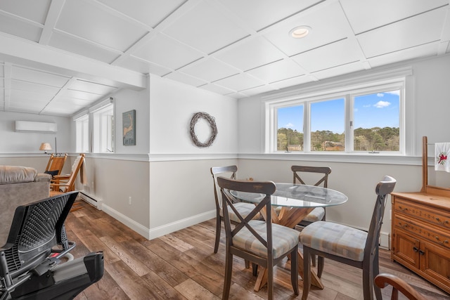 dining space featuring hardwood / wood-style flooring, baseboards, an AC wall unit, and a baseboard heating unit