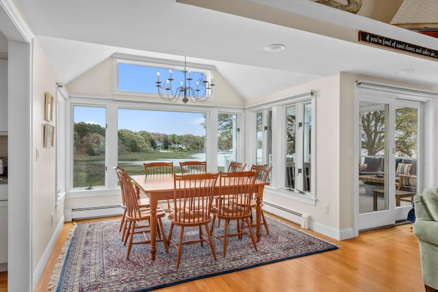 dining area with a baseboard radiator, healthy amount of natural light, a chandelier, wood finished floors, and vaulted ceiling