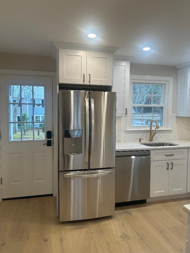 kitchen featuring decorative backsplash, white cabinets, appliances with stainless steel finishes, and sink