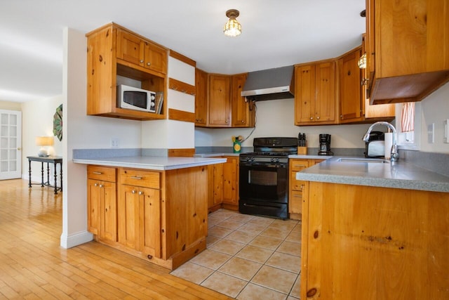 280 Schoolhouse Rd, Eastham, MA 02642 - kitchen with gas stove, wall chimney range hood, white microwave, a sink, and brown cabinets