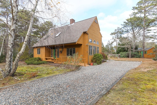 35 Pine Field Rd, Wellfleet, MA 02667 - view of front of property featuring a shingled roof, a chimney, gravel driveway, and an outbuilding