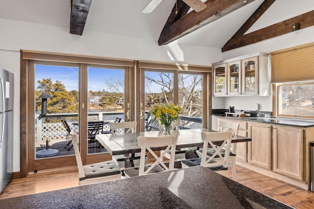 dining area with light wood-type flooring, vaulted ceiling with beams, and ceiling fan